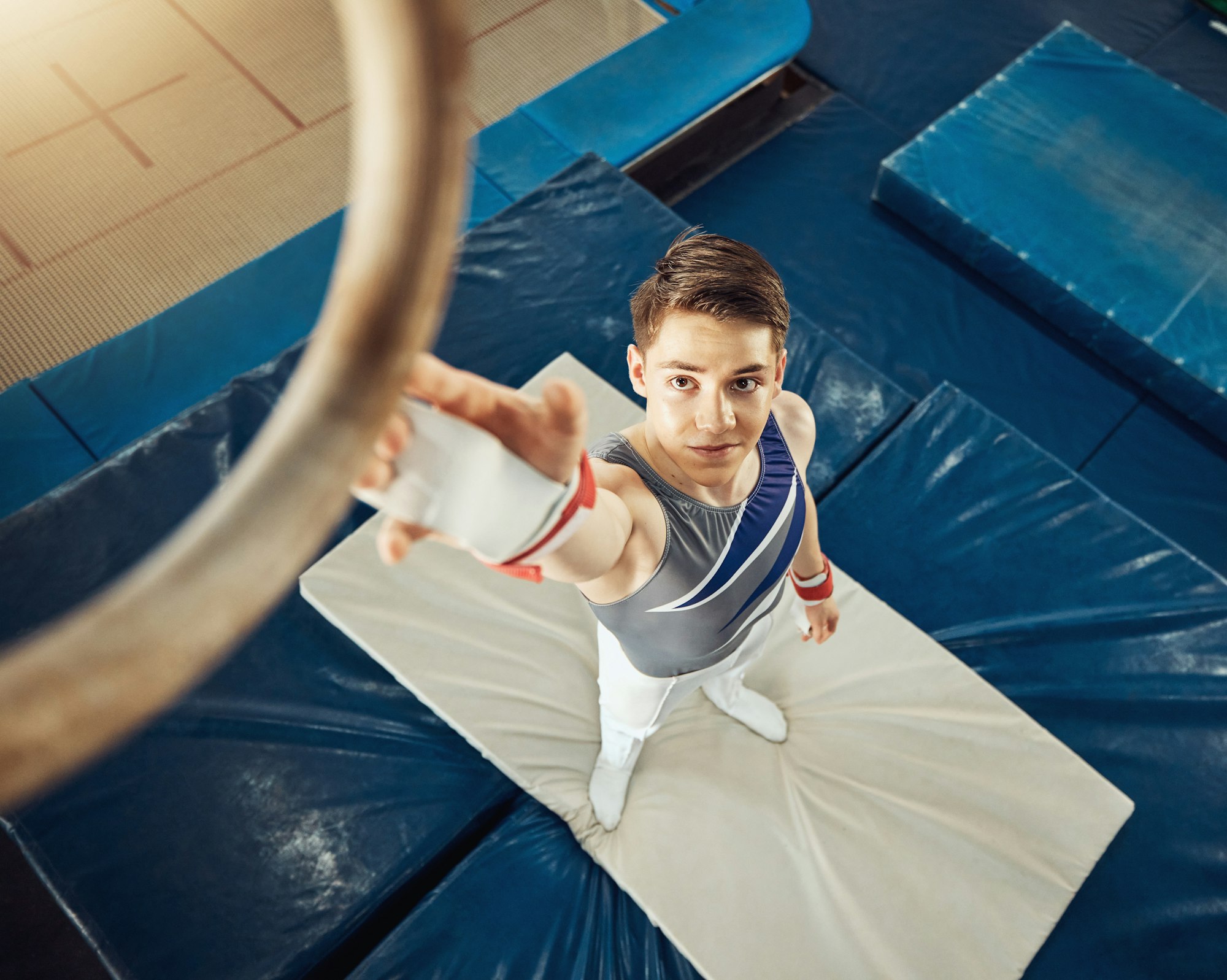 Sport, exercise and training ring for gymnastics exercise with a boy gymnast student in a gym. Top